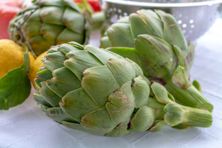 Cooking dinner with fresh green artichokes heads, tasty vegetarian foodの写真素材