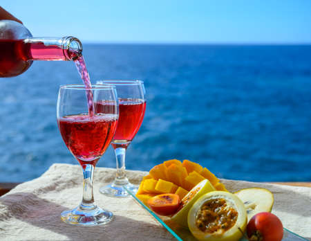 Two glasses of cold rose wine served outdoor with exotic fruits on tropical island La Palma, Canary islands, Spain with beautiful blue ocean viewの写真素材