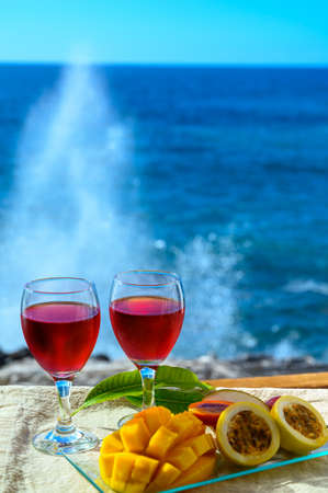 Two glasses of cold rose wine served outdoor with exotic fruits on tropical island La Palma, Canary islands, Spain with beautiful blue ocean viewの写真素材