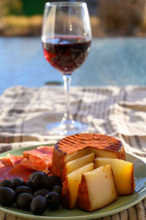 Tastes of Spain, jamon iberian, black olives, manchego cheese with red paprika and glass with red...