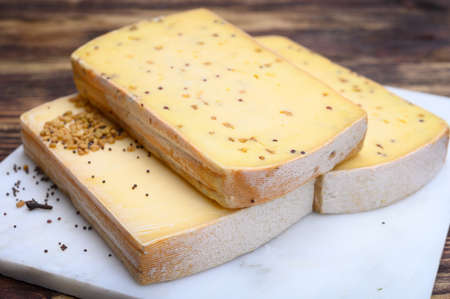 Belgian cheeses from abbey made from cow milk with monks beer, fenugreek and mustard seeds close up