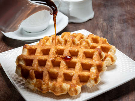 Tasty Belgian dessert, homemade Brussels sugar waffles with dark syrup close upの写真素材