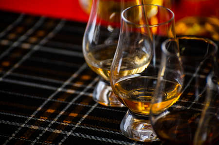 Special tulip-shaped glasses for tasting of Scotch whisky on distillery in Scotland, UK and dark tartan close upの写真素材