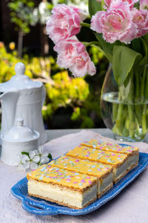 Four tompouce cakes with whipped cream and yellow icing served in sunny spring garden