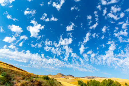 Andalusian summer landscape with yellow hills and blue sky with high white cloudsの写真素材