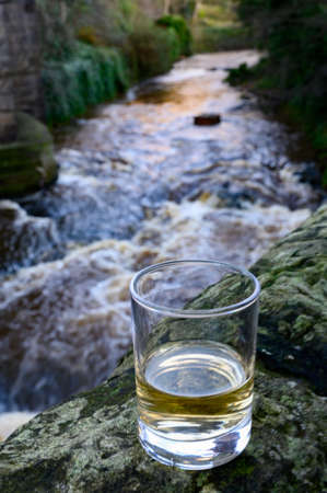 Scotch single malts or blended whisky spirits in glasses with water of river Spey on background, Scotland, UKの写真素材