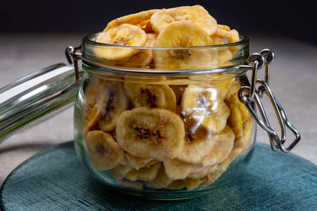Healthy sweet snack, crispy dehydrated unsugared banana chips in glass jar