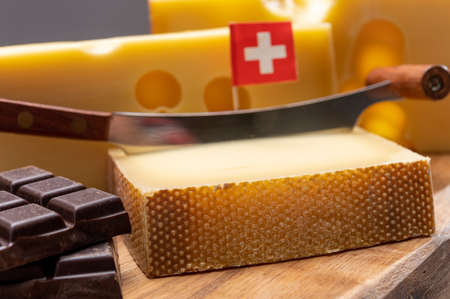 Tasty Swiss food, block of medium-hard yellow cheese emmental or emmentaler with round holes, matured gruyere and high quality milk chocolate close upの写真素材