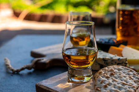 Whiskey and cheese pairing, tasting whisky glasses and plate with sliced cheeses close upの写真素材