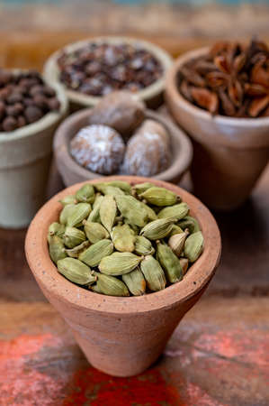 Indian spices collection, dried green cardamom pods and another spices in clay bowls close upの写真素材