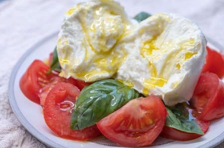 Ingredients for vegetarian caprese salad, buffalo mozzarella cheese, fresh basil, tomatoes, olive...