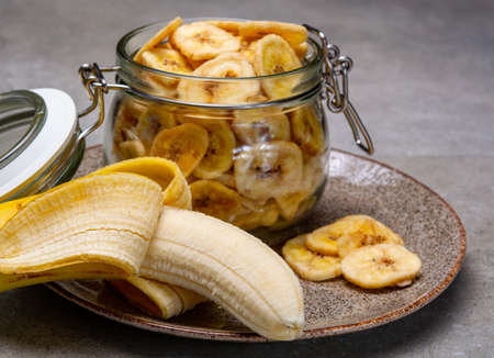Healthy sweet snack, crispy dehydrated unsugared banana chips in glass jarの写真素材