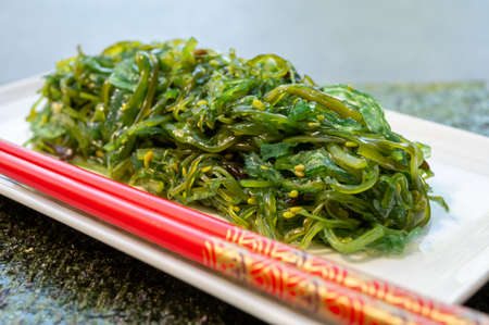 Green fresh oriental seaweed salad served with chopsticks close upの写真素材