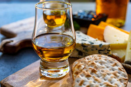 Whiskey and cheese pairing, tasting whisky glasses and plate with sliced cheeses close upの写真素材