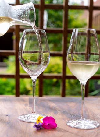 Summer tasting of cold white grape wine on sunny garden terrace with wooden pergolaの写真素材