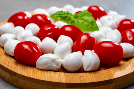 Italian food, fresh fresh green basil, white mini mozzarella cheese and red cherry tomatoes close upの写真素材