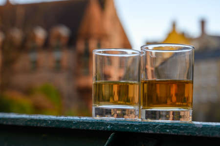 Scotch single malts or blended whiskey spirits in glasses with old houses of Edinburgh city on background, Scotland, UKの写真素材