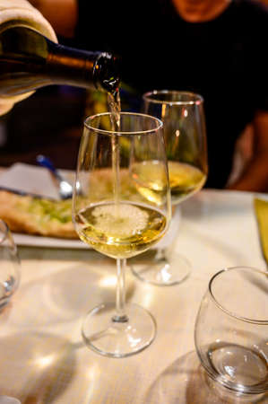 Pouring in glass cold dry white wine in outdoor cafe at night in Italy close upの写真素材