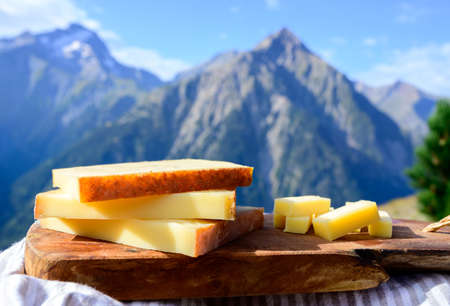 Cheese collection, French comte, beaufort or abondance cow milk cheese served outdoor with Alps mountains peaks in summer on backgroundの写真素材