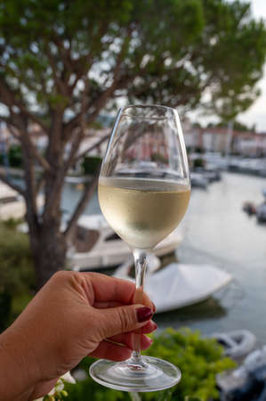 Tasting of local cold white wine in summer with sail boats haven of Port grimaud on background, Provence, Var, Franceの写真素材