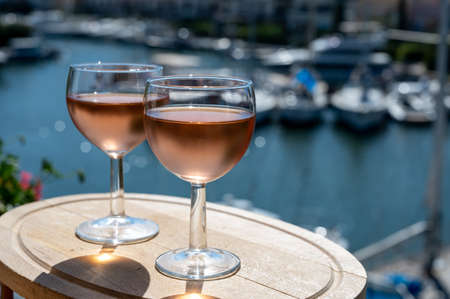 Tasting of local cold rose wine in summer with sail boats haven of Port grimaud on background,...