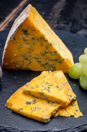 British matured yellow cheese blue shropshire, close up on black stone