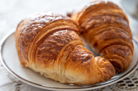 Two fresh baked puff croissants, traditional French breakfast close up