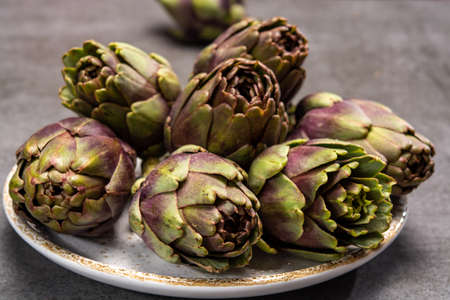 Fresh french petit violet artichokes heads cultivted in Brittany, France close up