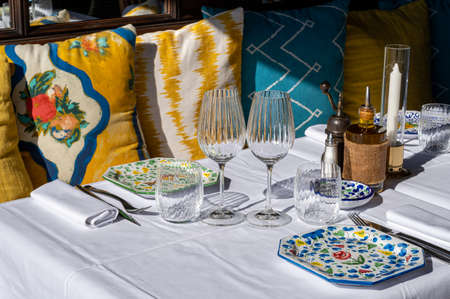 Before lunch time, empty stylish cafes with served tables waiting for guests in sunny Saint-Tropez,...