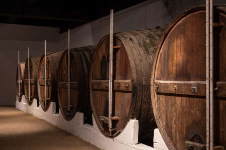Old porto lodge with rows of oak wooden casks for slow aging of fortified ruby or tawny porto wine in Vila Nova de Gaia, north of Portugalの写真素材