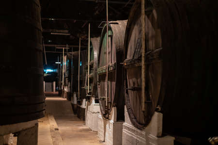 Old porto lodge with rows of oak wooden casks for slow aging of fortified ruby or tawny porto wine in Vila Nova de Gaia, north of Portugalの写真素材