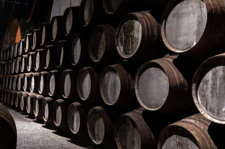Old porto lodge with rows of oak wooden casks for slow aging of fortified ruby or tawny porto wine in Vila Nova de Gaia, north of Portugalの写真素材