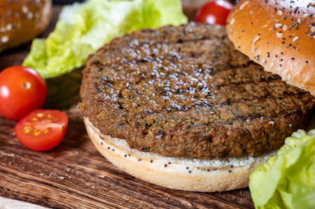 Making tasty vegetarian burgers from plant based grilled burgers, fresh bakes buns and organic vegetables close upの写真素材
