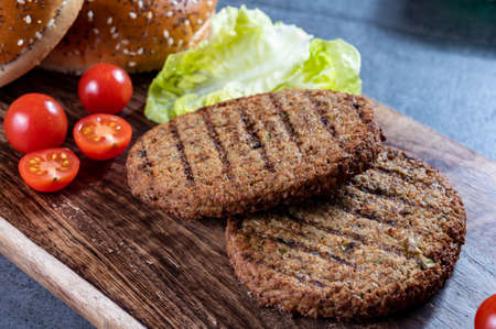 Making tasty vegetarian burgers from plant based grilled burgers, fresh bakes buns and organic vegetables close upの写真素材