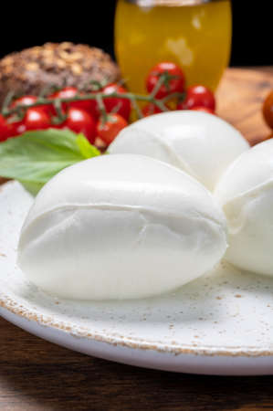 Cheese collection, white balls of soft Italian cheese mozzarella, served with red cherry tomatoes,...