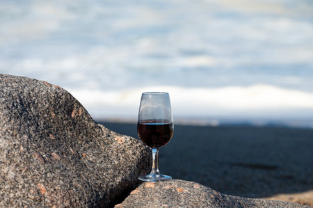 Wine in glass on sandy beach with view on waves of Atlantic ocean near Vila Nova de Gaia and city of Porto, Portugalの写真素材