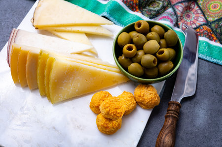 Spanish snacks tapas, variety of sliced goat, sheep, manchego cheeses, green olives, served in Andalusian interiorの写真素材
