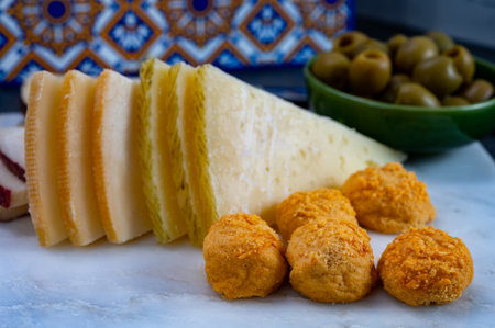 Spanish snacks tapas, variety of sliced goat, sheep, manchego cheeses, green olives, served in Andalusian interiorの写真素材