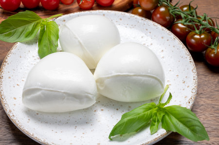 Cheese collection, white balls of soft Italian cheese mozzarella, served with red cherry tomatoes,...