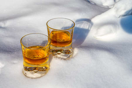 Glasses of cold scotch single malt whiskey on white snow close upの写真素材