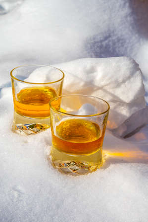 Glasses of cold scotch single malt whiskey on white snow close upの写真素材