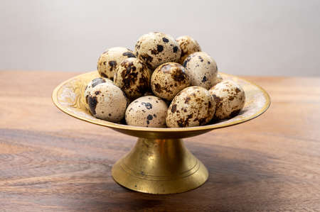 Fresh small spotted partridge eggs on bronze plate close upの写真素材