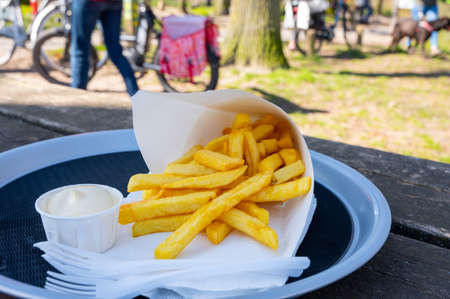 Eatiog of street or take away food fresh baked french fried potatoes chips in paper coneの写真素材