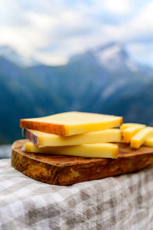 Cheese collection, French comte, beaufort or abondance cow milk cheese served outdoor with Alps mountains peaks in summer on backgroundの写真素材