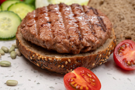 Making tasty vegetarian vegan hamburger from plant based soya beans burger, organic bun with seeds and fresh garden vegetablesの写真素材