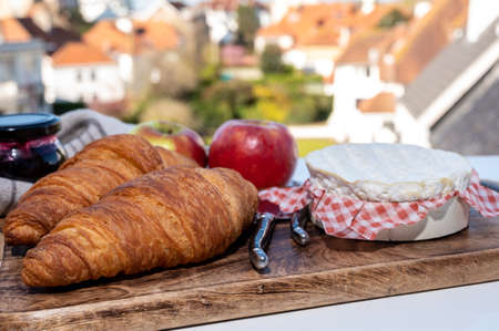 French breakfast with fresh baked croissants and cheeses from Normandy, camembert and neufchatel served outdoor with nice French village viewの写真素材