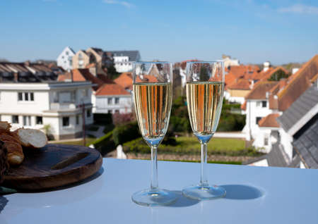 Drinking of brut champagne sparkling wine in flute glasses on outdoor cafe or bistro terrace in France on sunny dayの写真素材
