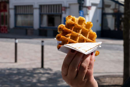 Eating of fresh baked hot Belgian sugar waffles, street food in Brugesの写真素材