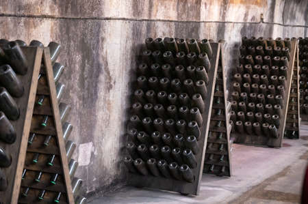 Champagne sparkling wine production in bottles in racks in dark underground cellar, Reims,...