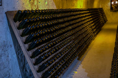 Champagne sparkling wine production in bottles in racks in dark underground cellar, Reims,...
